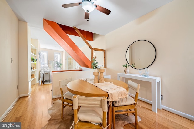 dining space with built in shelves, light wood-type flooring, and ceiling fan