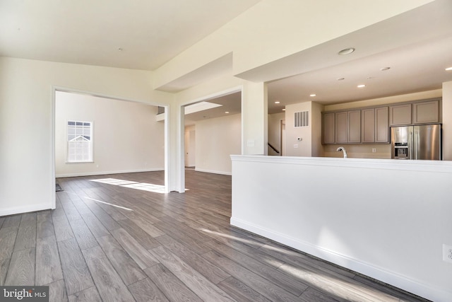 kitchen with stainless steel refrigerator with ice dispenser, sink, and wood-type flooring