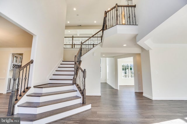 stairway with hardwood / wood-style floors, a high ceiling, and ornamental molding