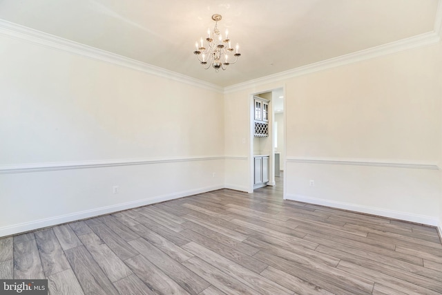 spare room with light hardwood / wood-style floors, ornamental molding, and a notable chandelier