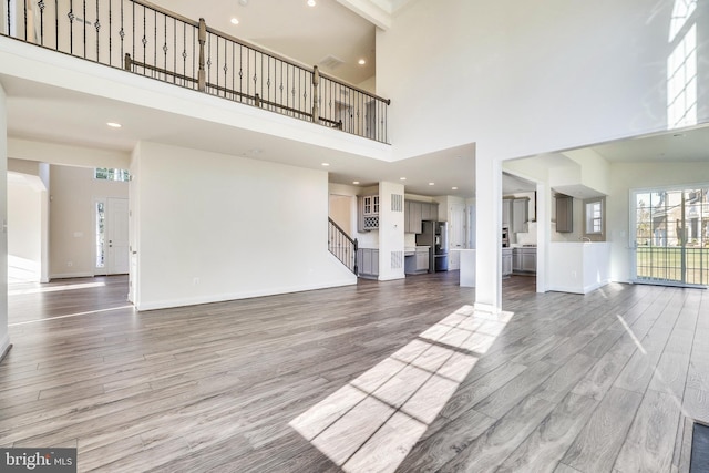 unfurnished living room featuring a high ceiling and hardwood / wood-style flooring