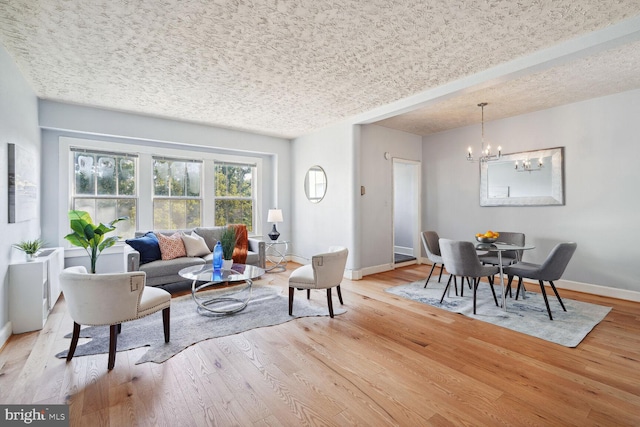 living room featuring a textured ceiling, light wood-type flooring, and an inviting chandelier