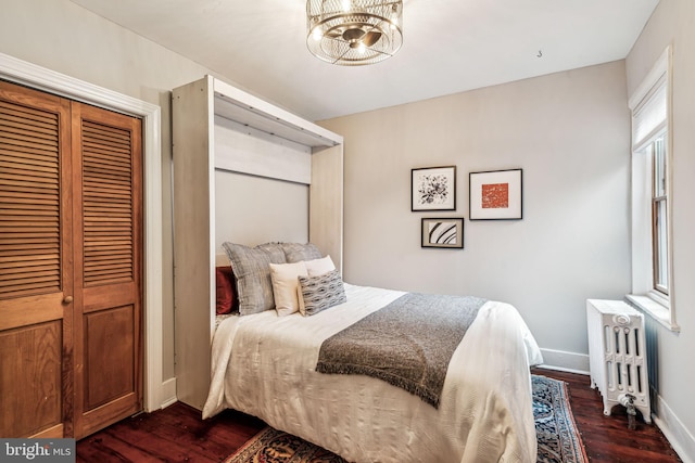 bedroom with radiator heating unit, dark hardwood / wood-style flooring, a closet, and a notable chandelier