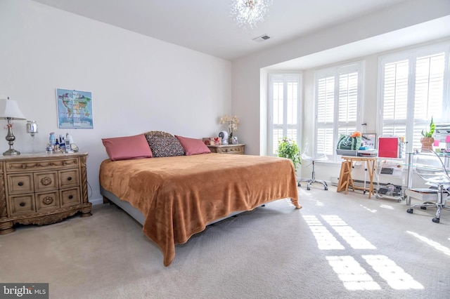 bedroom featuring light colored carpet and an inviting chandelier