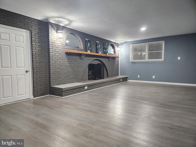 unfurnished living room featuring hardwood / wood-style flooring and a brick fireplace