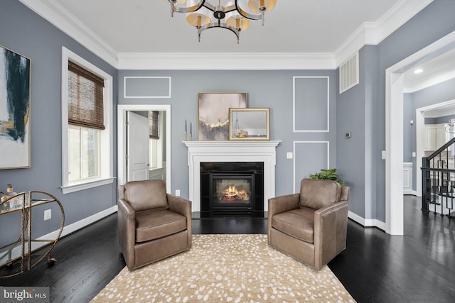 living area featuring a chandelier, dark hardwood / wood-style floors, and ornamental molding