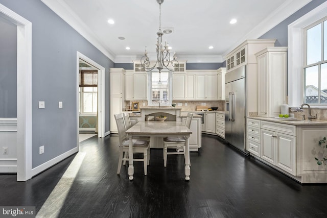 dining area featuring dark wood-type flooring, a notable chandelier, crown molding, and sink