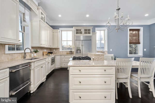 kitchen featuring a center island, built in appliances, tasteful backsplash, decorative light fixtures, and light stone counters