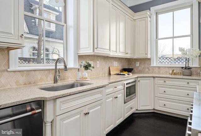 kitchen with dishwasher, sink, white cabinets, and light stone counters