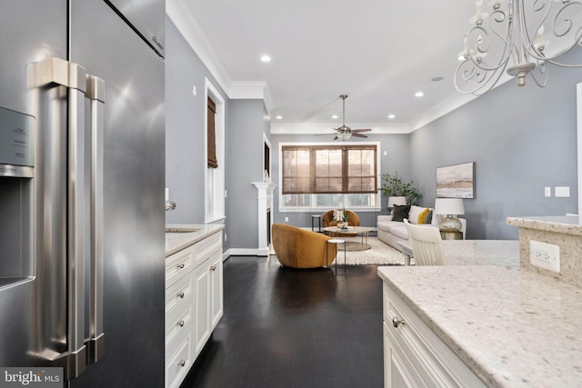 kitchen featuring high end refrigerator, light stone counters, ornamental molding, ceiling fan, and white cabinets