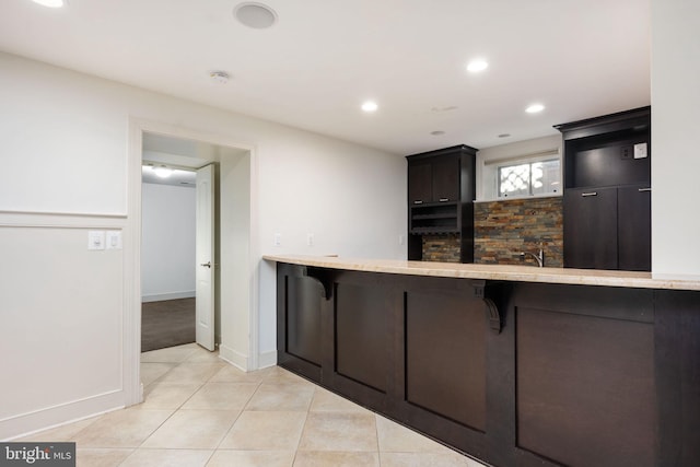 kitchen featuring kitchen peninsula, light tile patterned floors, and a breakfast bar area