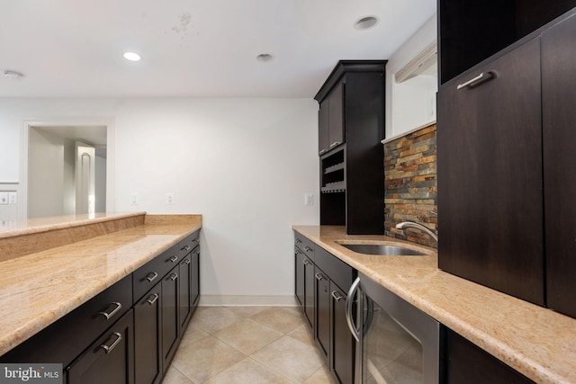 kitchen with light tile patterned flooring, light stone counters, wine cooler, and sink