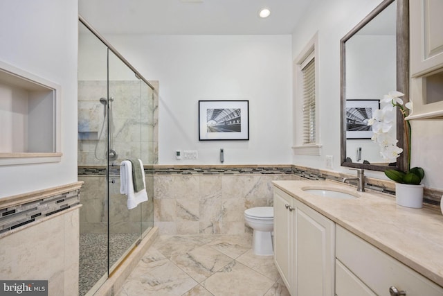 bathroom featuring vanity, toilet, an enclosed shower, and tile walls