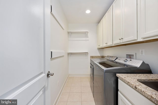 laundry room featuring separate washer and dryer, light tile patterned flooring, and cabinets