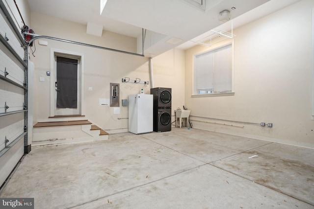 garage with electric panel, stacked washer and dryer, white fridge, and sink