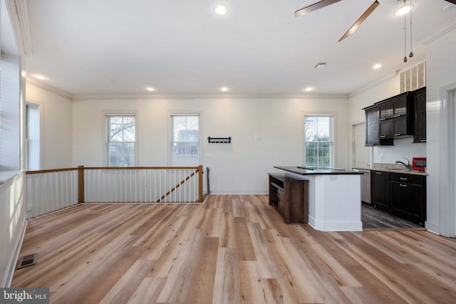 kitchen featuring a wealth of natural light, a kitchen island, ornamental molding, and light wood-type flooring