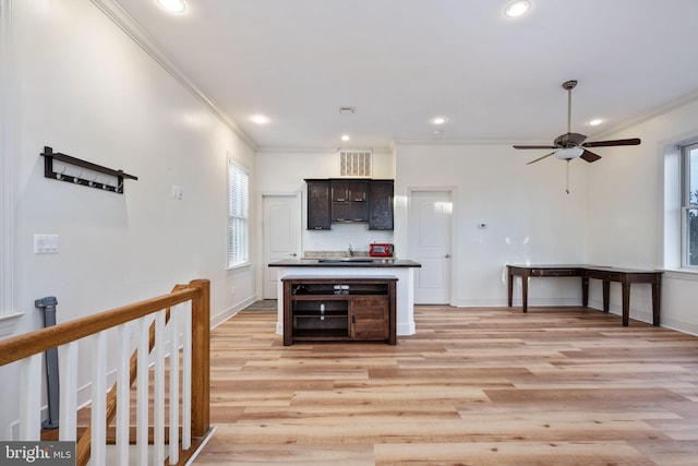 kitchen with dark brown cabinetry, ornamental molding, and light hardwood / wood-style flooring