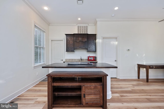 kitchen featuring a wealth of natural light, a center island, ornamental molding, dark brown cabinets, and light wood-type flooring