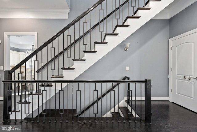 stairs featuring ornamental molding and an inviting chandelier