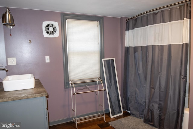 bathroom featuring hardwood / wood-style floors, vanity, and shower / bathtub combination with curtain