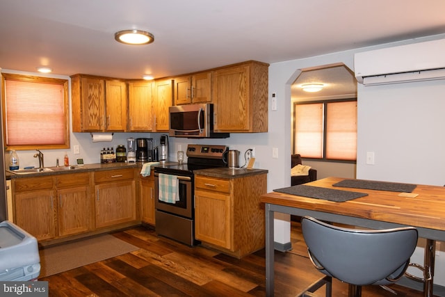 kitchen with a wall mounted air conditioner, dark hardwood / wood-style floors, sink, and stainless steel appliances