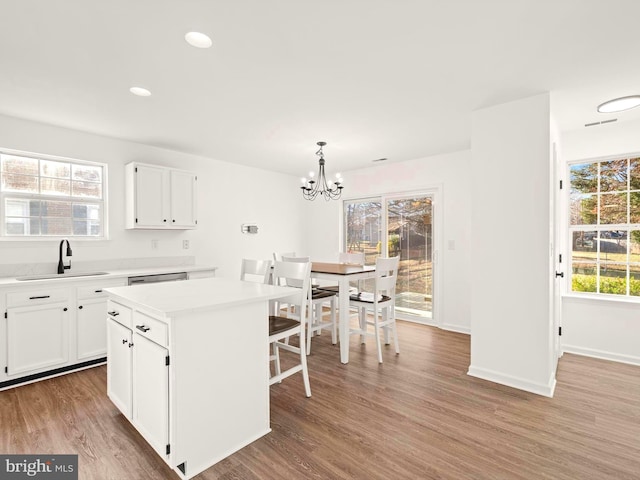 kitchen featuring sink, decorative light fixtures, white cabinetry, hardwood / wood-style flooring, and a kitchen island