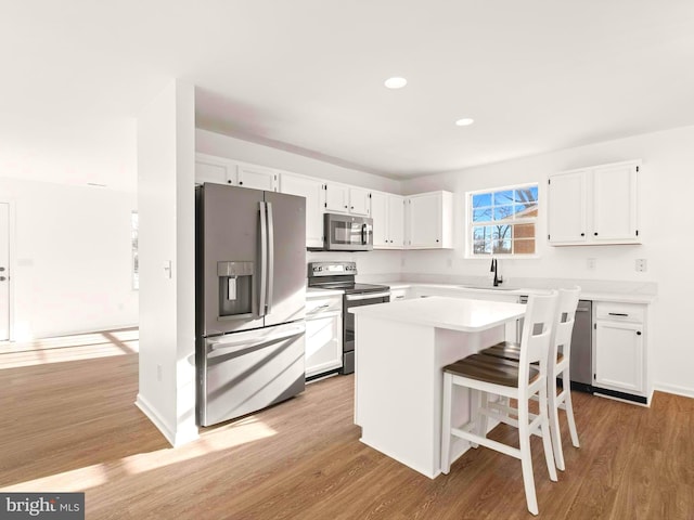 kitchen with a center island, a kitchen bar, white cabinetry, and stainless steel appliances