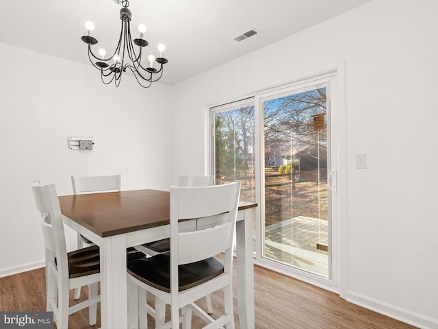 dining room with wood-type flooring and an inviting chandelier