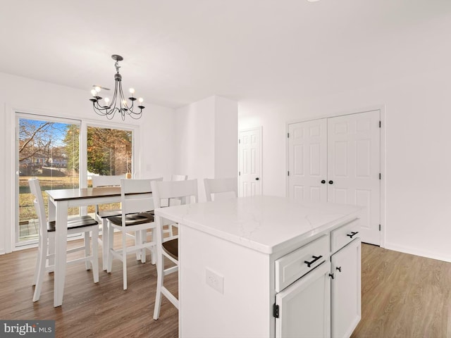 kitchen with pendant lighting, light hardwood / wood-style flooring, a kitchen island, white cabinetry, and a chandelier