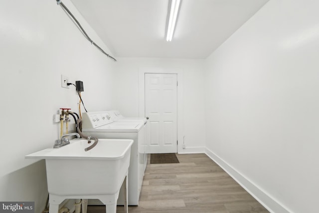 washroom with independent washer and dryer, light hardwood / wood-style flooring, and sink