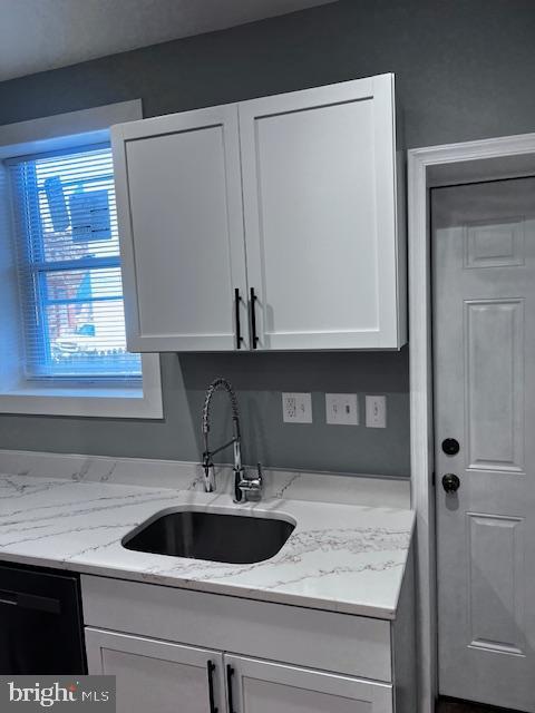 kitchen featuring dishwasher, white cabinetry, light stone countertops, and sink