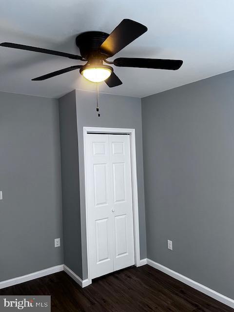 unfurnished bedroom featuring ceiling fan, dark hardwood / wood-style floors, and a closet