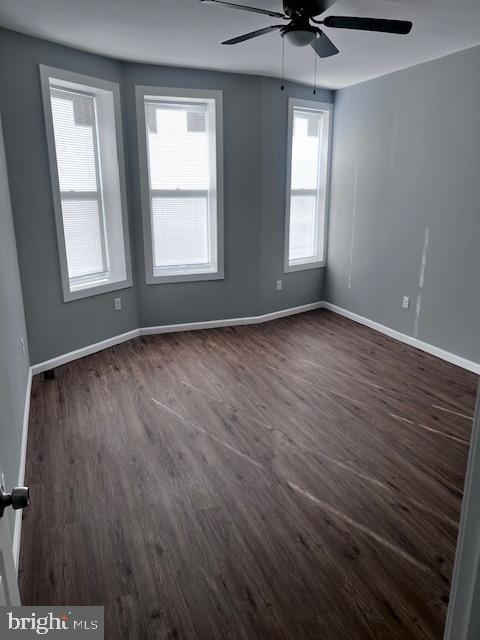 unfurnished room featuring ceiling fan and dark wood-type flooring