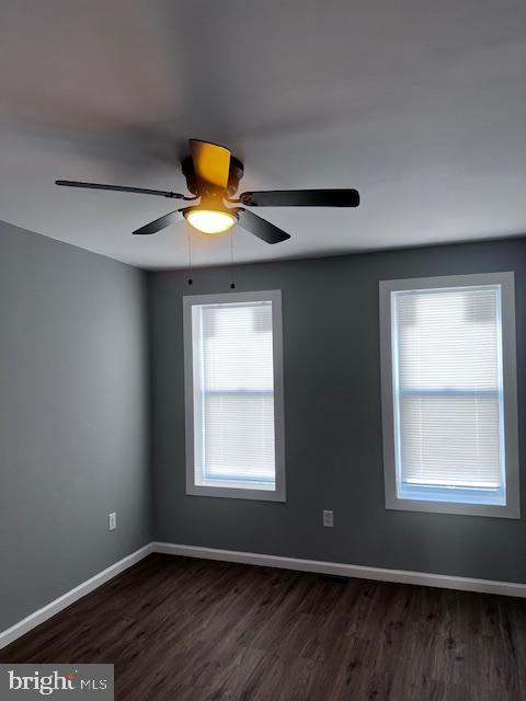 empty room with dark hardwood / wood-style floors and ceiling fan