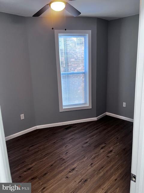 empty room featuring ceiling fan and dark wood-type flooring