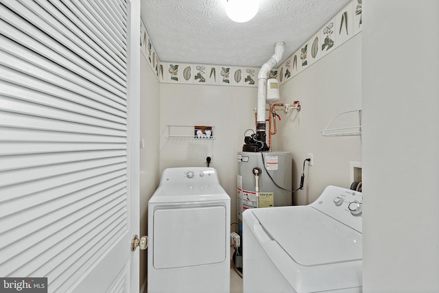 laundry area with a textured ceiling, water heater, and washing machine and clothes dryer