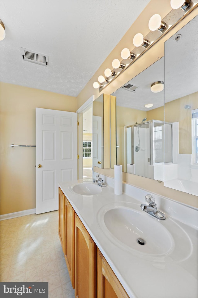 bathroom featuring a textured ceiling, walk in shower, a healthy amount of sunlight, and vanity