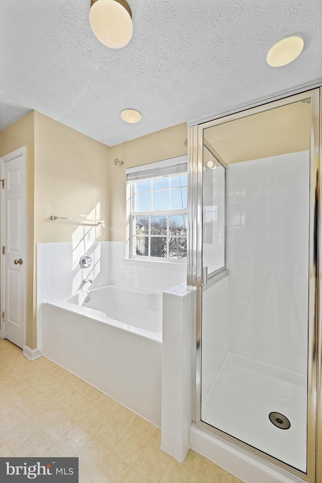 bathroom featuring a textured ceiling and shower with separate bathtub