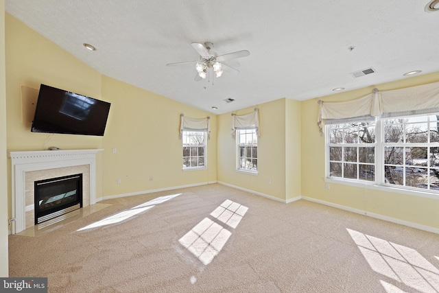 unfurnished living room with a textured ceiling, lofted ceiling, a high end fireplace, ceiling fan, and light carpet