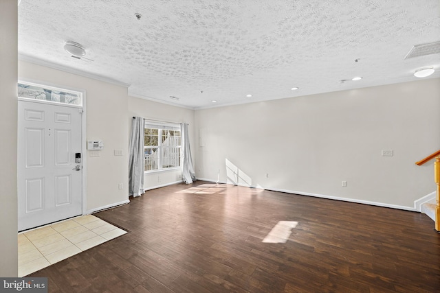 foyer entrance featuring a textured ceiling, ornamental molding, and wood-type flooring