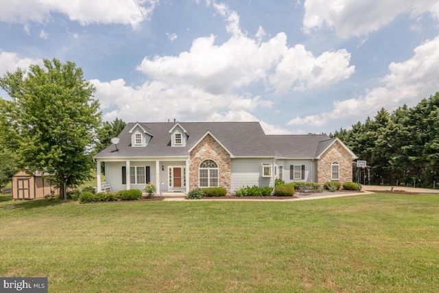 cape cod home with covered porch, a front lawn, and a storage shed