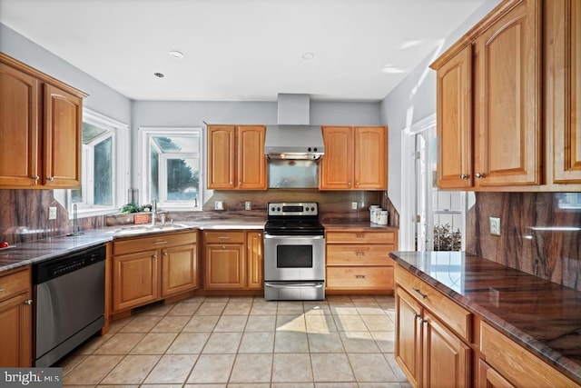 kitchen featuring stainless steel appliances, decorative backsplash, wall chimney exhaust hood, sink, and light tile patterned flooring