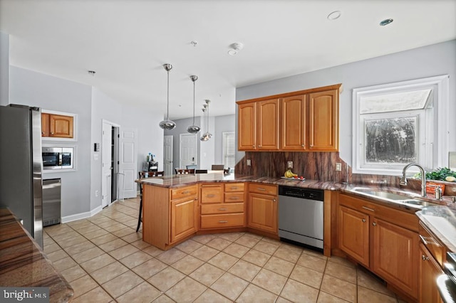 kitchen featuring kitchen peninsula, pendant lighting, light tile patterned floors, appliances with stainless steel finishes, and sink