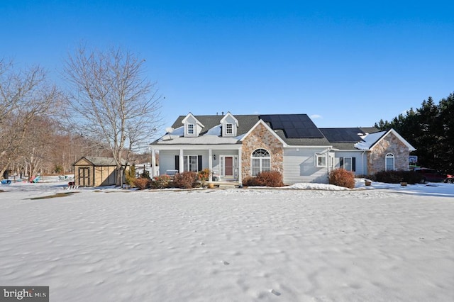 cape cod house featuring a storage unit and solar panels