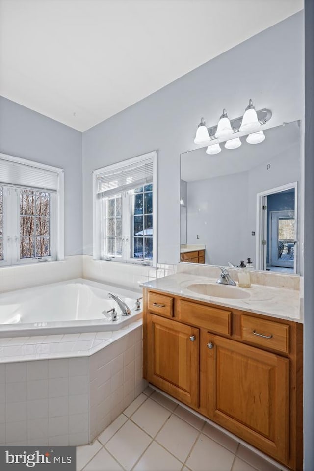 bathroom featuring tile patterned flooring, vanity, and tiled tub