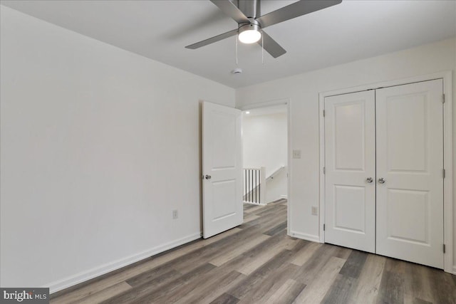 unfurnished bedroom with wood-type flooring, a closet, and ceiling fan