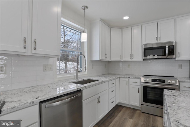 kitchen featuring pendant lighting, appliances with stainless steel finishes, sink, and white cabinets