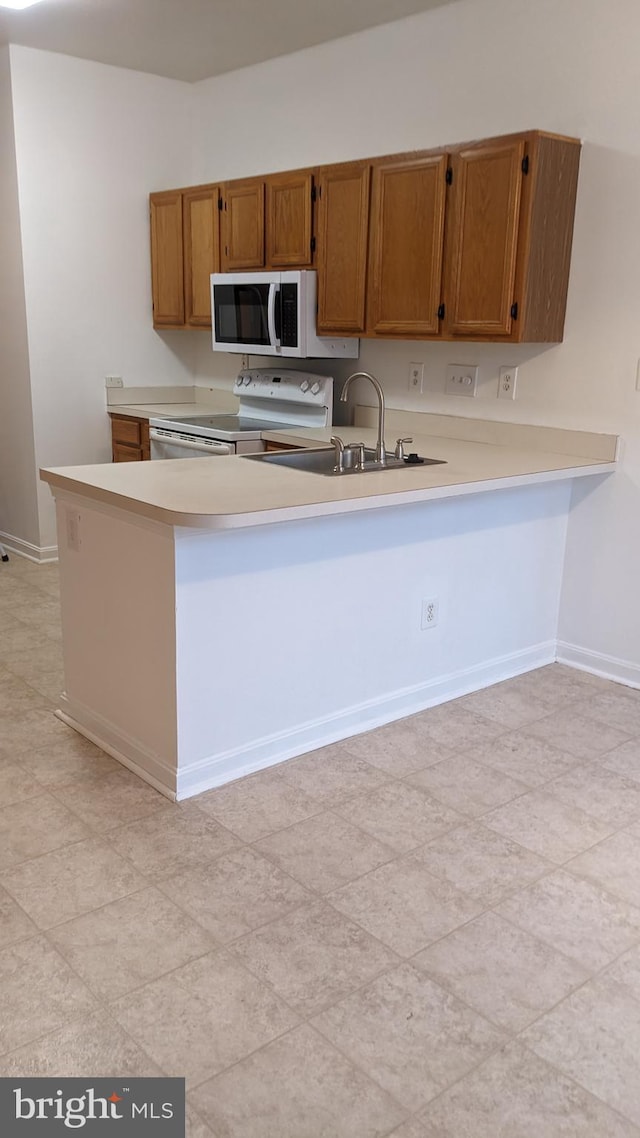 kitchen with sink, white appliances, and kitchen peninsula