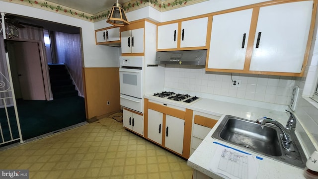 kitchen with range hood, white cabinetry, sink, decorative backsplash, and white appliances