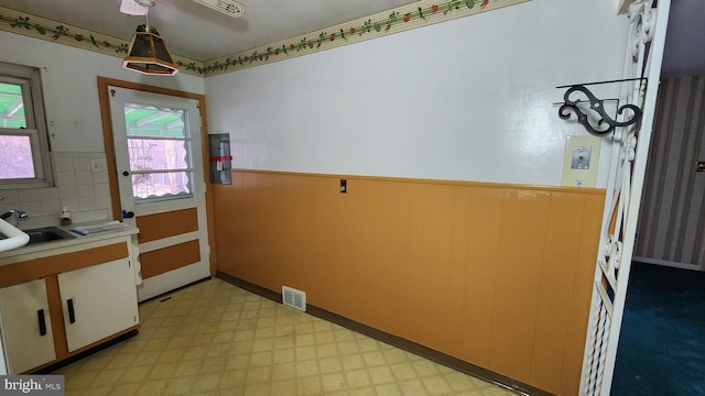 kitchen featuring hanging light fixtures, sink, and wood walls